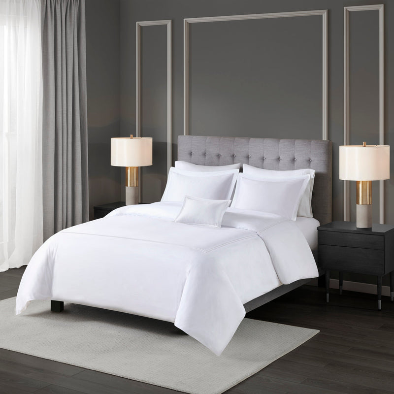 Bettwäsche-Set mit weißer Einziehdecke und dekorativer Randverarbeitung auf einem Bett