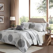 Graues Steppdecken-Set mit geometrischem Kreismuster auf einem Bett