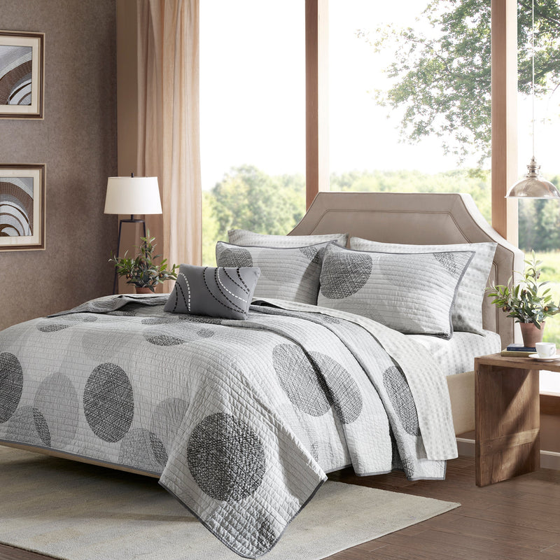Graues Steppdecken-Set mit geometrischem Kreismuster auf einem Bett
