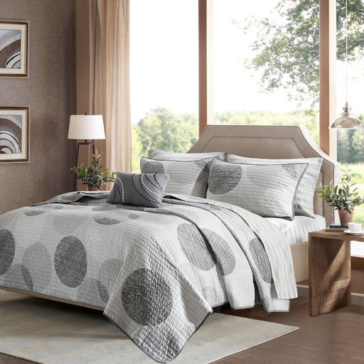 Graues Steppdecken-Set mit geometrischem Kreismuster auf einem Bett