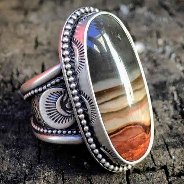 Silberfarbener Ring mit ovalem gestreiftem Schmuckstein und dekorativer Fassung
