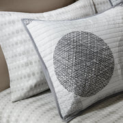Graues Steppdecken-Set mit geometrischem Kreismuster auf einem Bett