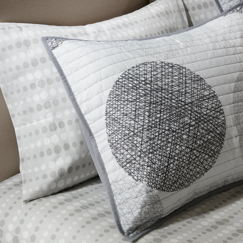 Graues Steppdecken-Set mit geometrischem Kreismuster auf einem Bett