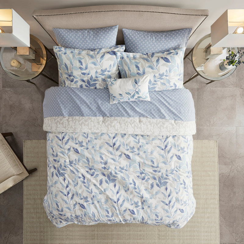 Blaues 8-teiliges Bettwäsche-Set mit wendbarer Bettdecke und Blättermuster auf einem Bett