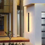 Lineare Außenwandleuchte mit schmalem, hochformatigem Leuchtkörper an einer modernen Fassade