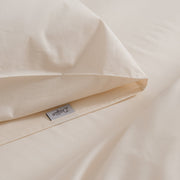 Cremefarbenes Bettwäsche-Set mit Bettbezug und Kissenbezügen auf einem Bett