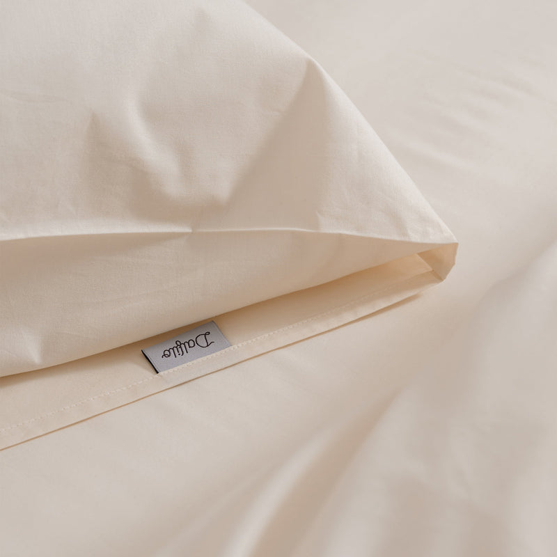 Cremefarbenes Bettwäsche-Set mit Bettbezug und Kissenbezügen auf einem Bett