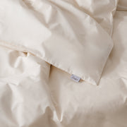 Cremefarbenes Bettwäsche-Set mit Bettbezug und Kissenbezügen auf einem Bett