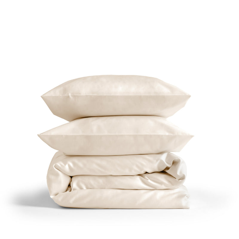 Cremefarbenes Bettwäsche-Set mit Bettbezug und Kissenbezügen auf einem Bett