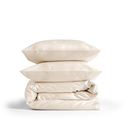 Cremefarbenes Bettwäsche-Set mit Bettbezug und Kissenbezügen auf einem Bett