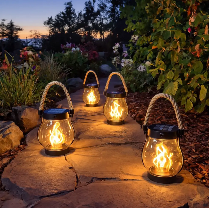 Schwarze Solarleuchte in Laternenform mit Seilgriff und leuchtendem Flammeneffekt im Garten