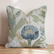 Blaues Dekokissen mit floralem Distelmotiv auf einem Sofa
