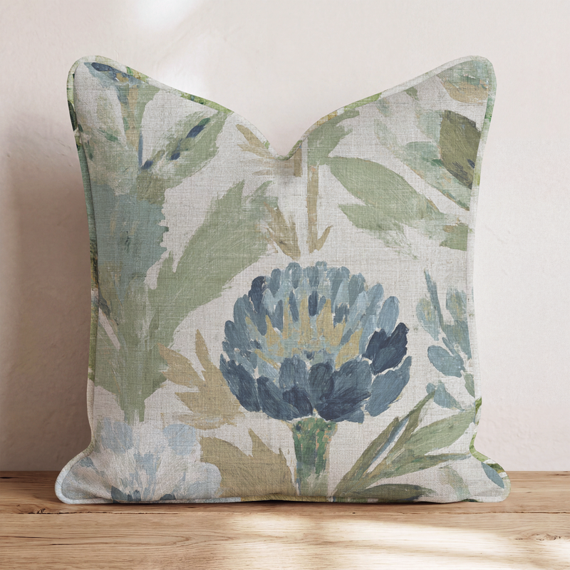Blaues Dekokissen mit floralem Distelmotiv auf einem Sofa