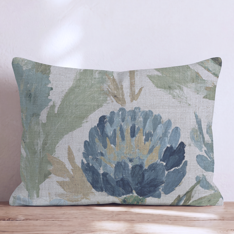 Blaues Dekokissen mit floralem Distelmotiv auf einem Sofa