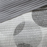 Graues Steppdecken-Set mit geometrischem Kreismuster auf einem Bett