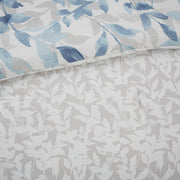 Blaues 8-teiliges Bettwäsche-Set mit wendbarer Bettdecke und Blättermuster auf einem Bett