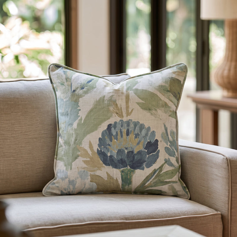 Blaues Dekokissen mit floralem Distelmotiv auf einem Sofa