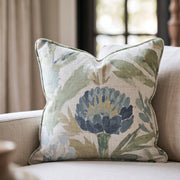 Blaues Dekokissen mit floralem Distelmotiv auf einem Sofa