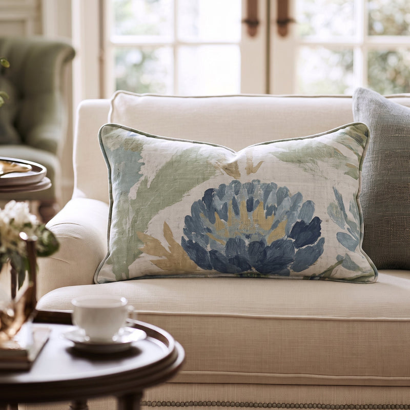 Blaues Dekokissen mit floralem Distelmotiv auf einem Sofa