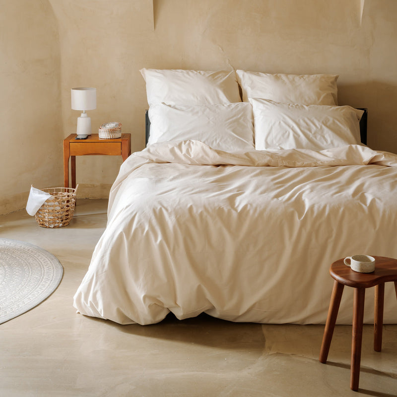 Cremefarbenes Bettwäsche-Set mit Bettbezug und Kissenbezügen auf einem Bett