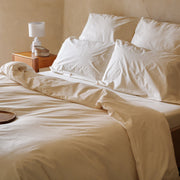 Cremefarbenes Bettwäsche-Set mit Bettbezug und Kissenbezügen auf einem Bett