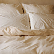 Cremefarbenes Bettwäsche-Set mit Bettbezug und Kissenbezügen auf einem Bett