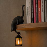 Katzenfigur mit leuchtender LED-Laterne an einer Regalkante