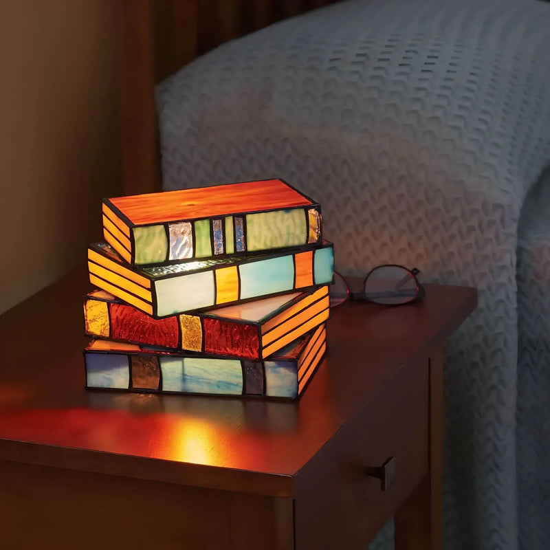 Dekorative Tischlampe in Buchform mit bunten Glasflächen auf einem Beistelltisch