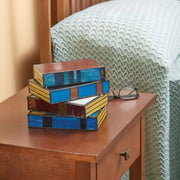 Dekorative Tischlampe in Buchform mit bunten Glasflächen auf einem Beistelltisch