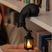 Katzenfigur mit leuchtender LED-Laterne an einer Regalkante