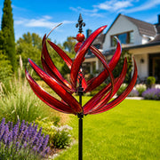 Dekoratives Windspiel in Blumenform mit geschwungenen Elementen und langem Stab im Garten